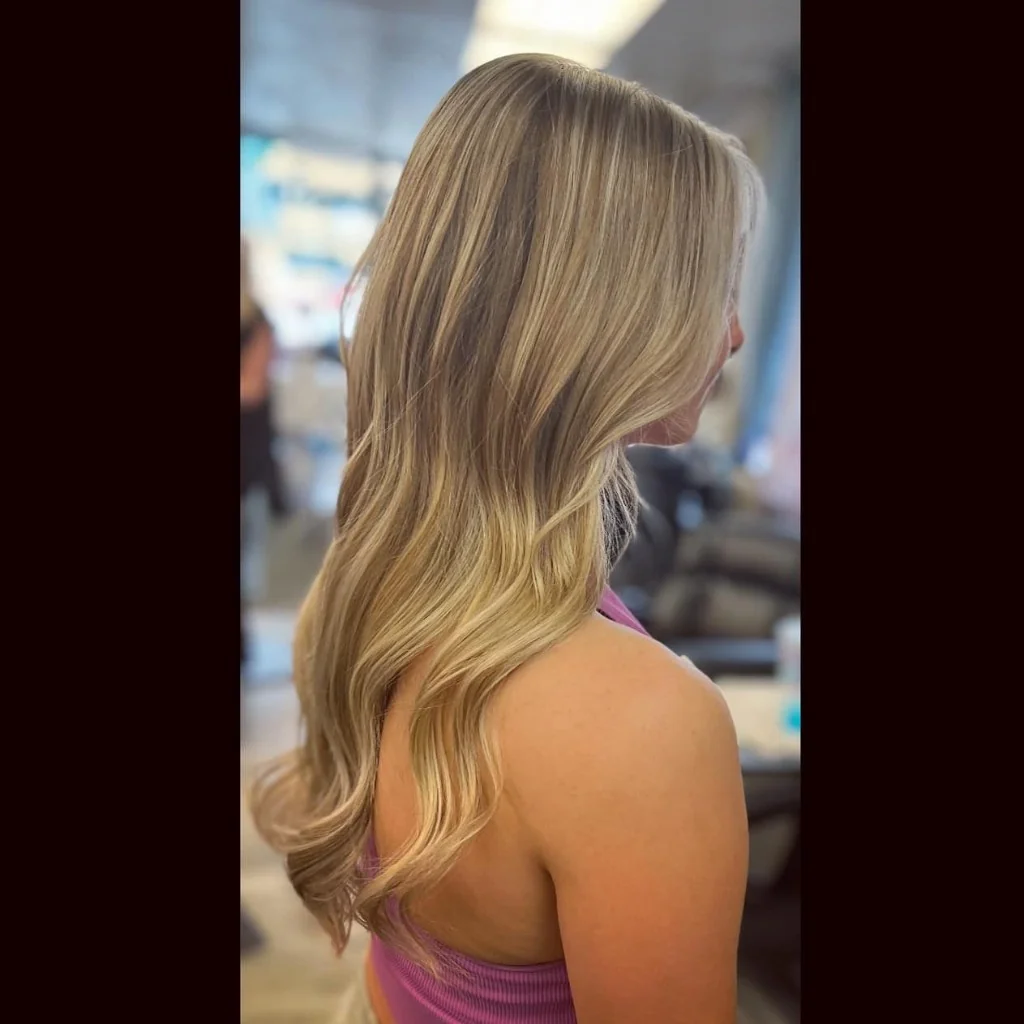 Long honey-blonde hair styled in loose waves, professional color and styling in Caro, Michigan.