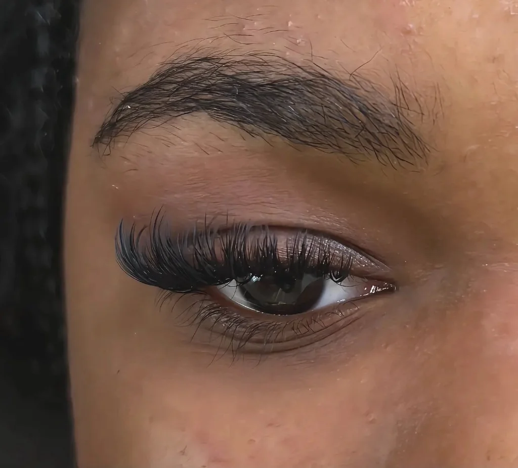 Close-up of one eye with long black volume lash extensions in a cat-eye style.