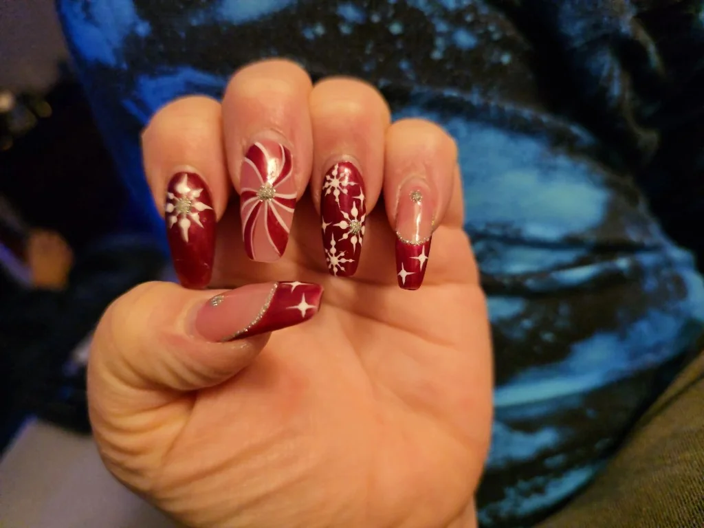 Hand with long almond nails in coordinated red, white and silver glitter holiday nail art.